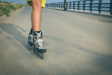 Rollerskater inline in action. Male legs shod in roller skates ride along the promenade