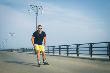 young man with inline skates ride in summer park seafront outdoor rollerskater