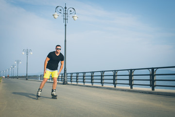 young man with inline skates ride in summer park seafront outdoor rollerskater