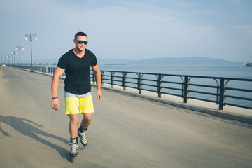 young man with inline skates ride in summer park seafront outdoor rollerskater