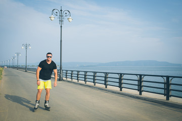 young man with inline skates ride in summer park seafront outdoor rollerskater