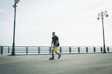 young man with inline skates ride in summer park seafront outdoor rollerskater