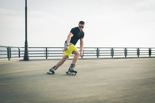 young man with inline skates ride in summer park seafront outdoor rollerskater