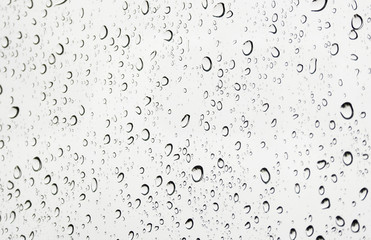 Rain water drops on car window glass during cloudy raining day.