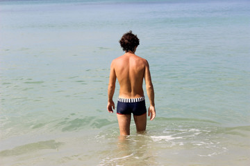 Fototapeta na wymiar man walking through sea and splashing water. Vacations on seashore