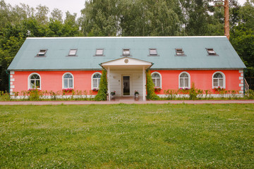 Obraz premium One-storeyed red house with green roof covered by ivy