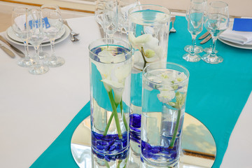 Callas put in a glass with blue stones on the bottom stand on a