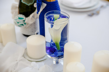 Table decor. Bud of calla flower put in a wineglass with blue st