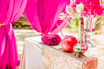Pink flowers and red pomegranate stands on the table behind an e