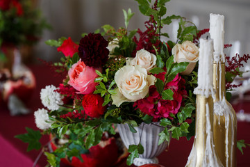 Rich red bouquet in Greek vase stand behind golden bottles with