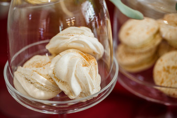White kisses put under a glass cover stand on a red tablecloth