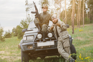 armed men near the machine in the forest. poaching. illegal hunting in the forest. commando....