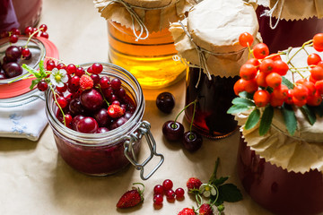 Fruit preserves and raw strawberries , cherries , rowans berries on a kitchen table, organic meal and dessert concept - obrazy, fototapety, plakaty