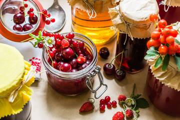 Fruit preserves and raw strawberries , cherries , rowans berries on a kitchen table, organic meal and dessert concept