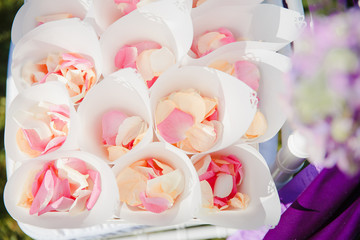 Fototapeta na wymiar Pink and beig rose petals lie on the envelopes in a basket