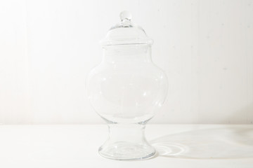 A glass bowl with cover stands on the white table