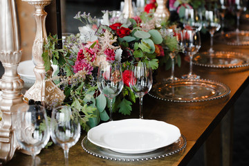 Glass plates and crockery lie on the brown dinner table surround