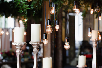 Dinner table decoration. Black lamp caps hang from a greenry on