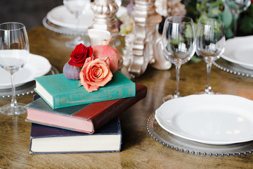 Aristocratic table decoration. Roses lie on the top of old books