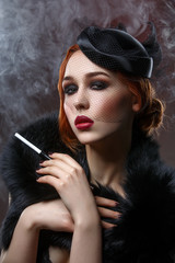 Beautiful girl with smoky eyes and red lips holding cigarette