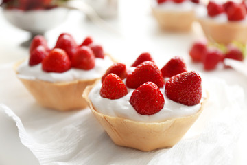 Tasty cakes with strawberries on white table