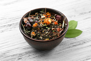 Dried tea in bowl on wooden background