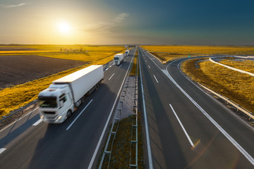 Three trucks on the freeway at idyllic sunset