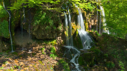 Obraz premium Woman standing next to a waterfall at the idyllic day
