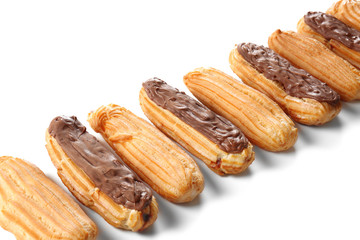 Delicious eclairs with chocolate in a row on white background