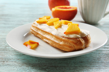 Delicious eclair with peach slices on plate