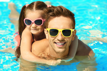 Handsome father with little daughter in swimming pool at water park