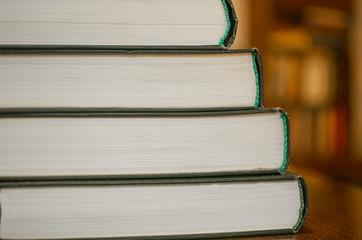 Book stack in the library room and blurred bookshelf for business and education. Back to school. Stack of books background. Many books piles. Distance education learning concept during quarantine.