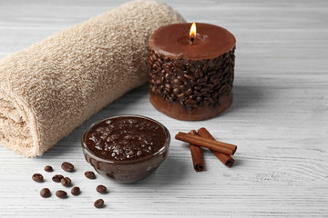 Body scrub and candle on wooden table