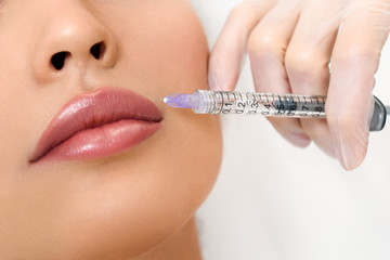 Young woman receiving cosmetic rejuvenation with syringe