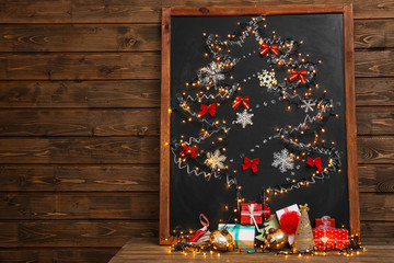 Beautiful Christmas tree drawn on board and decorated with garland, on wooden background