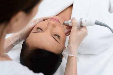 Obraz na płótnie Canvas Skillful beautician doing facial laser skincare procedure