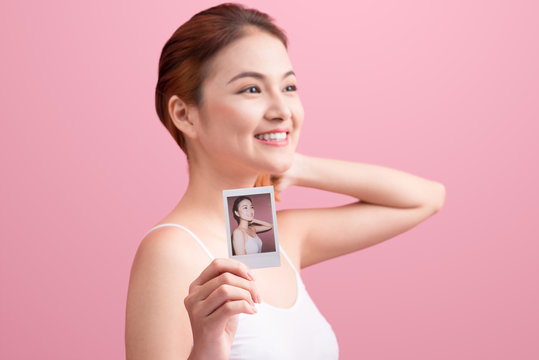 Young asian woman holding her polaroid picture on pink backgroun