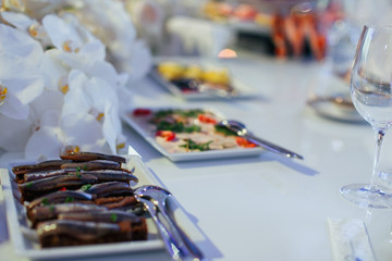 Tasty sprats lie on the square plate on white dinner table