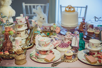 Cupcakes with pink flowers stand on the plates on the table full