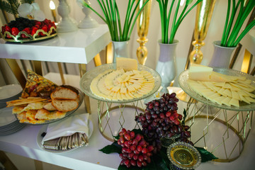 Cut cheese lies on the crystal plates behind grapes