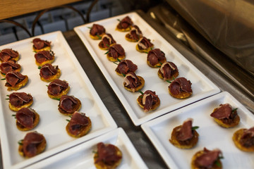 Red meat lies over a little pancakes on the square dishes