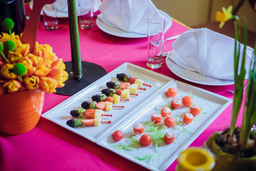 Cut fruits on the sticks served on square plates
