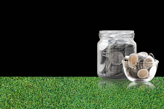coins in a glass jar on grass floor ,savings coins - Investment And Interest Concept saving money concept, growing money on piggy bank. isolated on black background