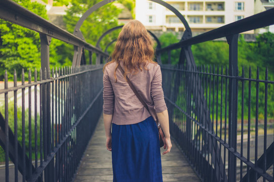 Young woman walking on steel bridgeq