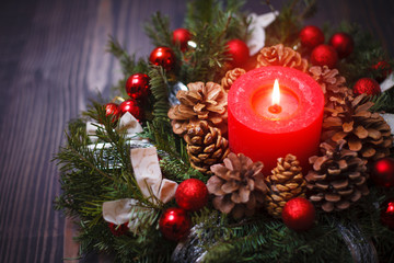 Red candle in a wreath of pine branches with Christmas balls