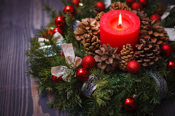 Red candle in a wreath of pine branches with Christmas balls