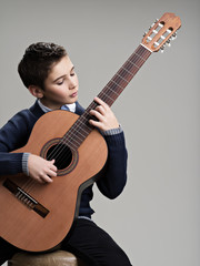 Obraz premium Caucasian boy playing on acoustic guitar.