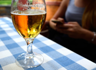 Glass of beer on a table in the restaurant and in the background woman's hands