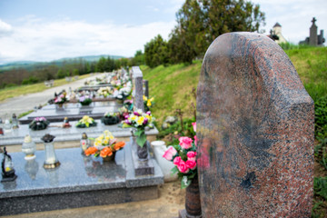 Close up of empty tombstone. Graves, tomb stones and crucifixes on traditional public cemetery. Votive candles lantern and flowers on tomb stones on graveyard in Slovakia
