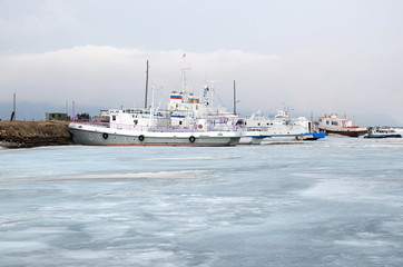 Ship and fisher boats on the dock in Large Goloustnoye Village. Baikal Lake